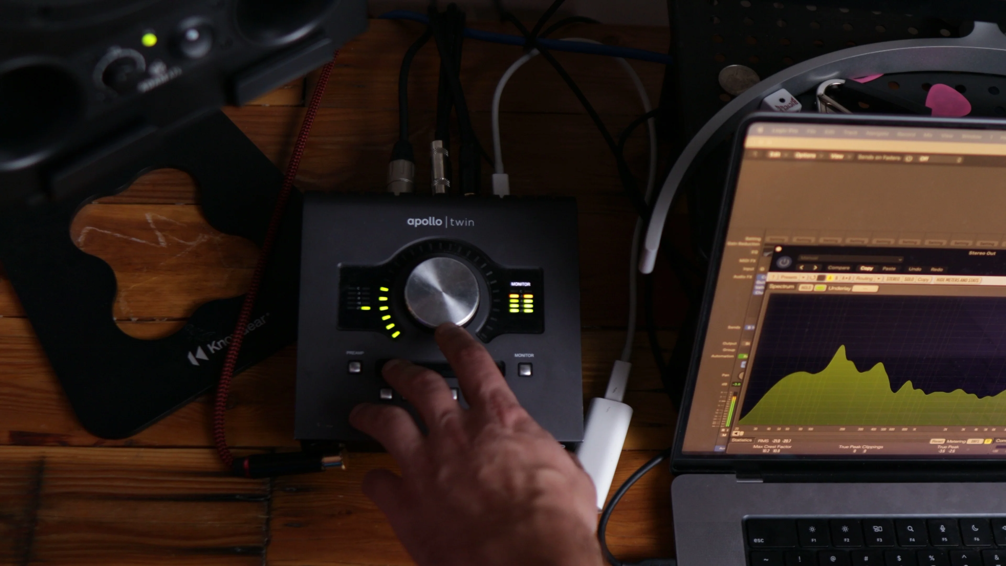 Hand adjusting gain level knob on Universal Audio Apollo Twin interface with LED meters displaying input levels