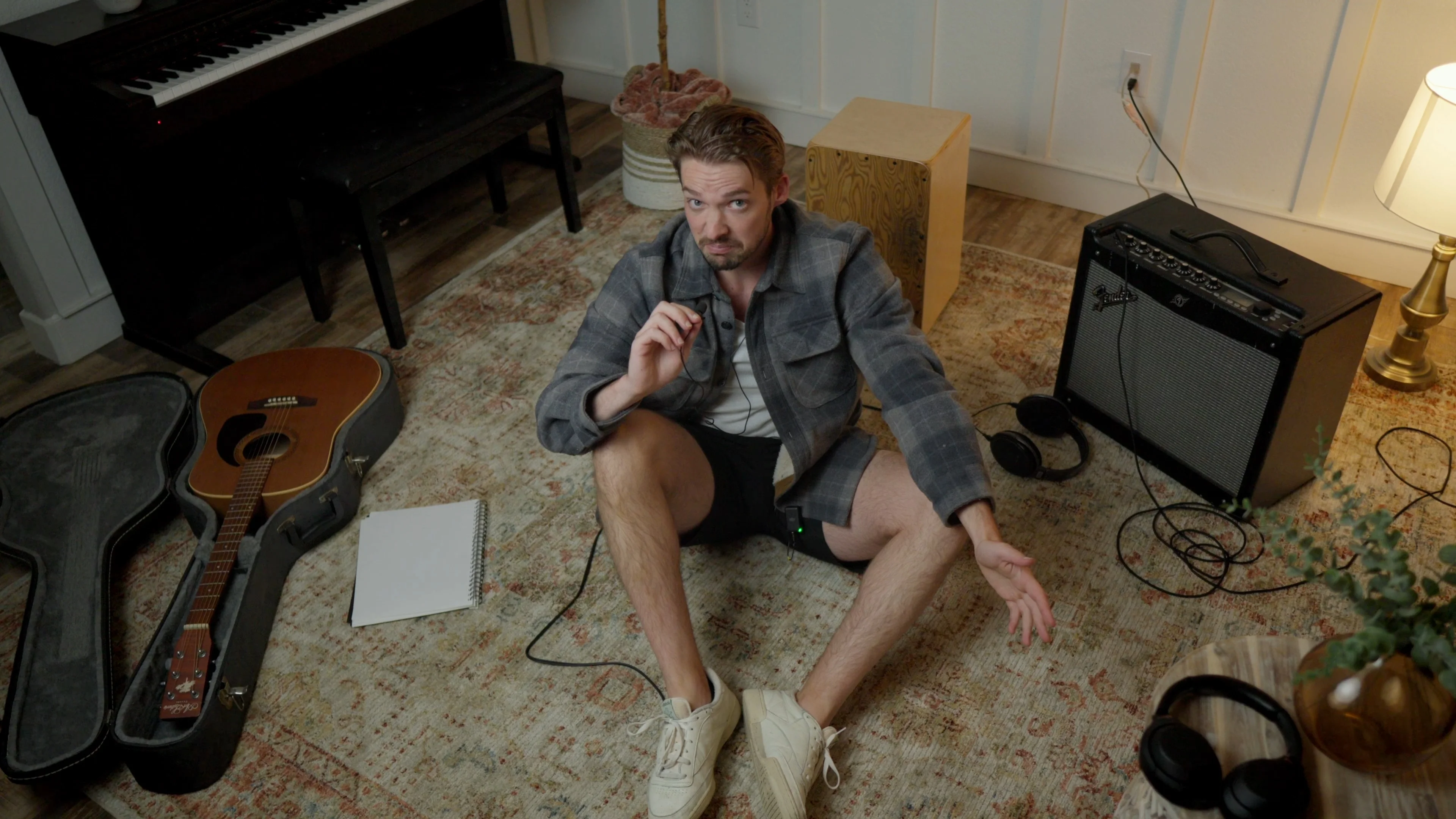 Mattie sitting on studio floor with acoustic guitar and notepad, developing a personal lyric-writing strategy