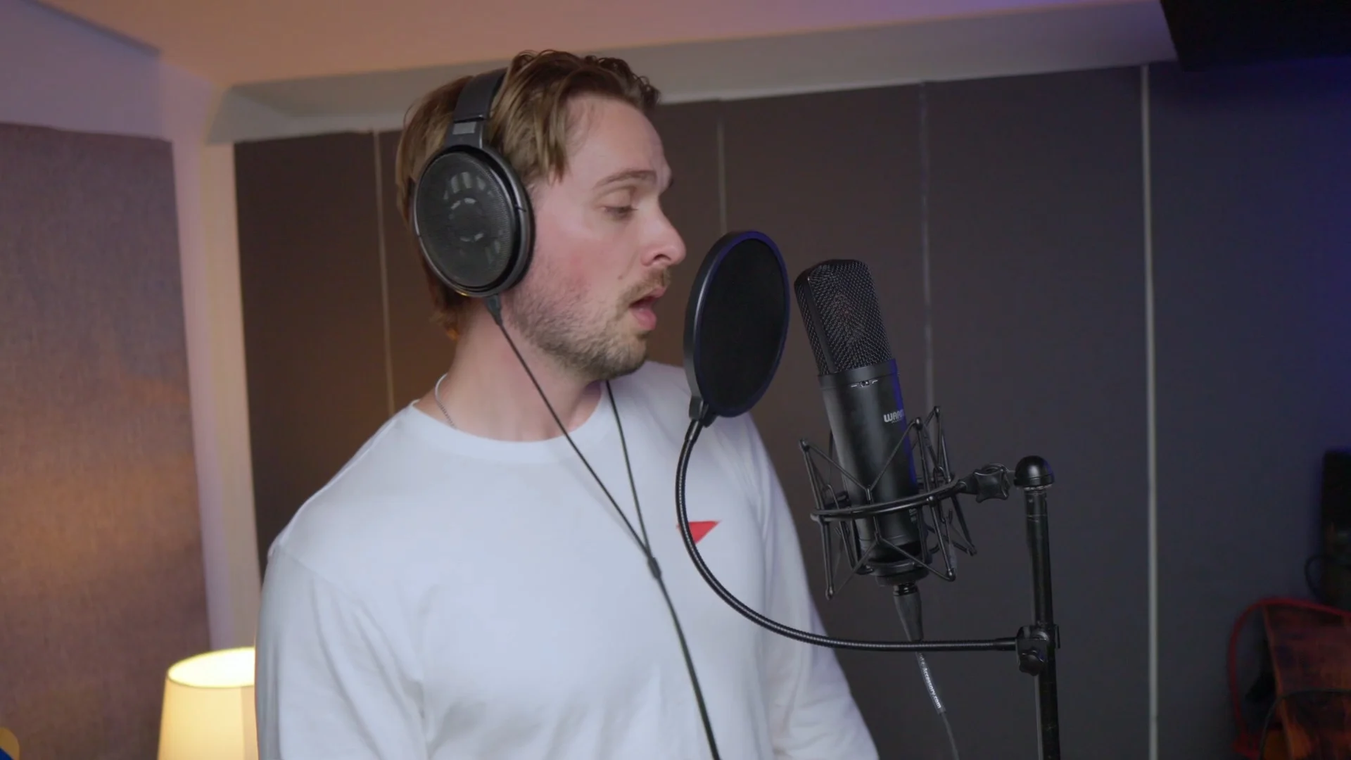 Mattie recording vocals with a condenser microphone in a DIY acoustic-treated vocal booth