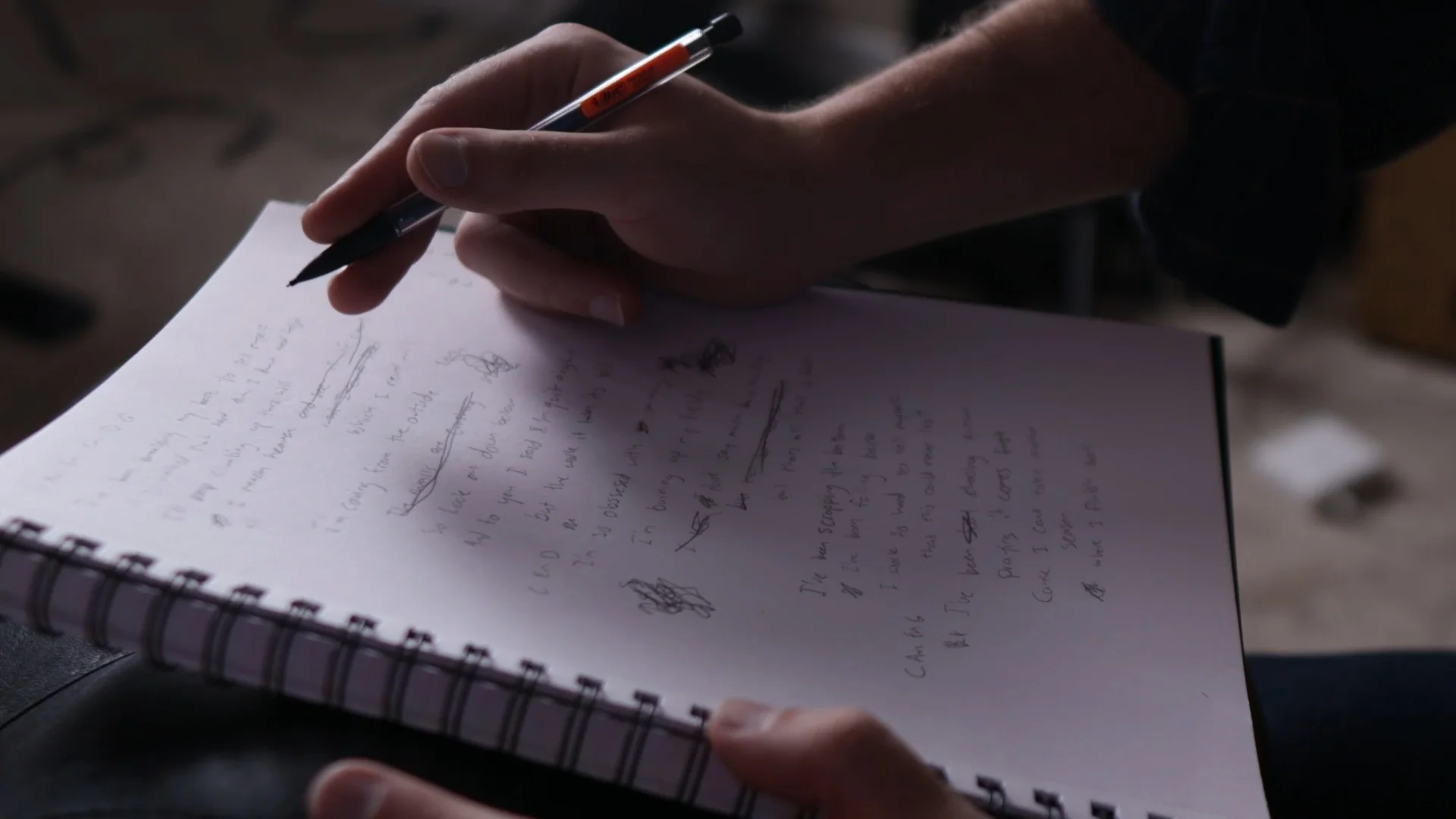 Mattie writing lyrics in a notebook, analyzing recurring songwriting themes