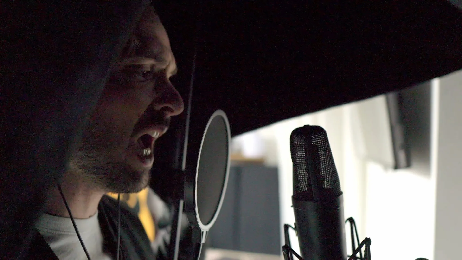 Close-up of Mattie singing into a condenser microphone while testing AI stem splitters for vocal isolation quality
