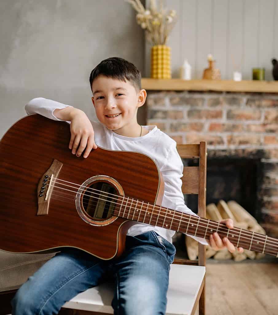 Smiling Child Posing with Acoustic Guitar